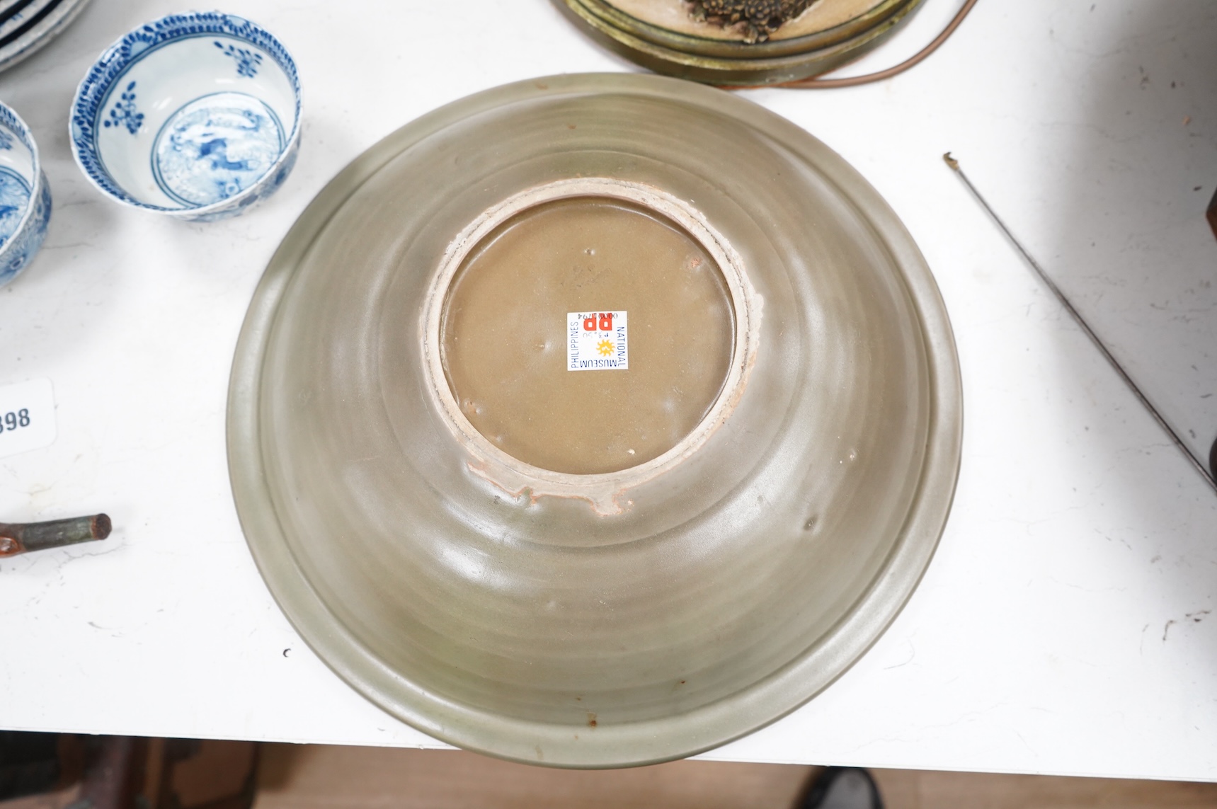 A 17th century Chinese celadon dish decorated in low relief, restored, 36cm in diameter